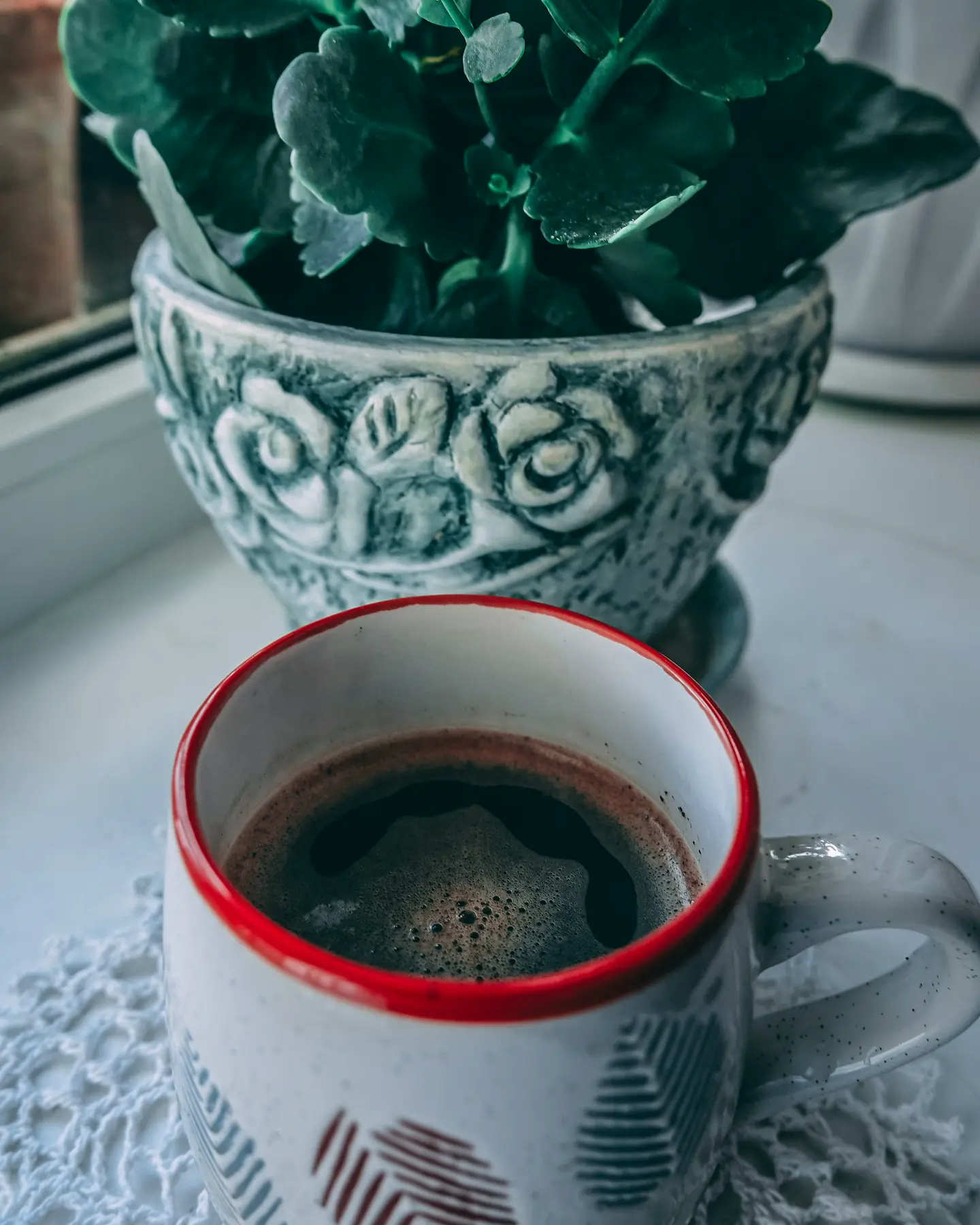 A ceramic mug beside a potted plant on a table